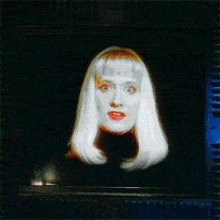 Holly waves her floating head around on a TV screen then ducks out of view while smiling.